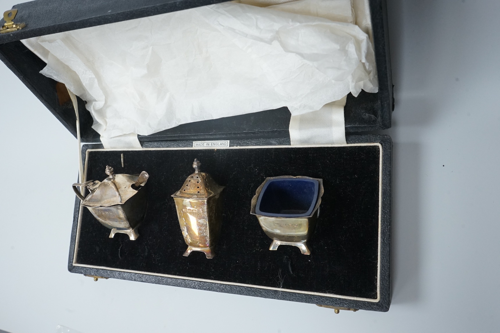 A pair of cased Elizabeth II silver three piece condiment sets, by William Adams Ltd, Birmingham, 1955, one spoon missing.